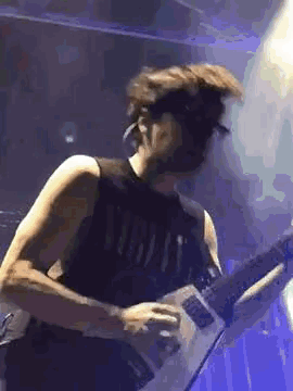 a man is playing a guitar on stage while wearing a nirvana shirt .