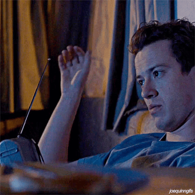 a man is sitting on a couch with a remote control in his hand