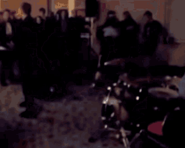 a blurred image of a man playing drums in a dark room