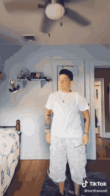 a tiktok video of a person standing in a bedroom with a ceiling fan