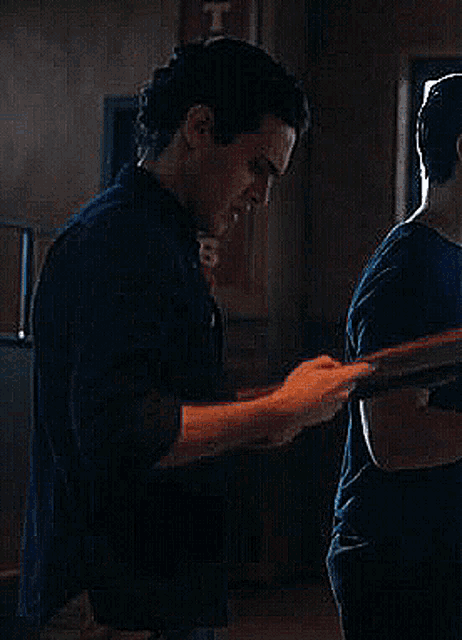 a man in a black shirt is standing in a dark room