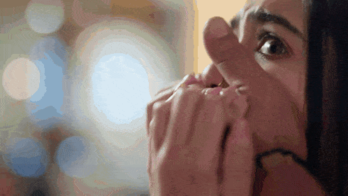 a woman covering her mouth with her hands while looking at something