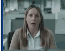 a woman is sitting at a desk in an office with her mouth open and a surprised look on her face .