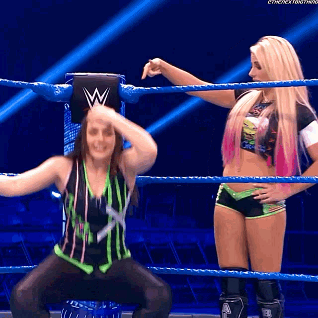 two women are in a wrestling ring and one of them has the letter w on her shirt