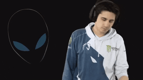a man wearing headphones stands in front of an alien head