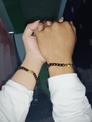 a man and a woman holding hands with matching bracelets
