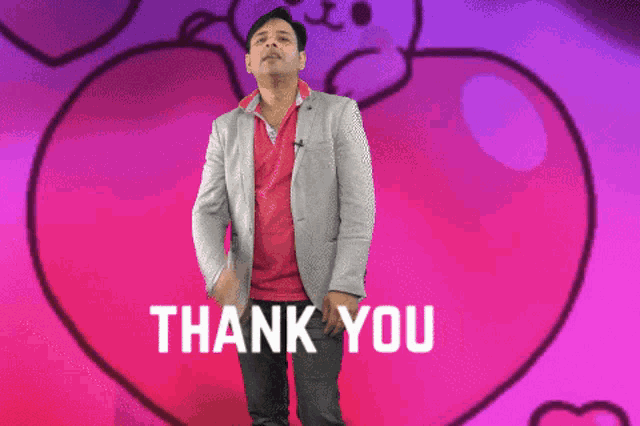 a man in a suit holds his hand to his chest in front of a pink heart that says thank you