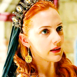 a close up of a woman wearing a crown and earrings