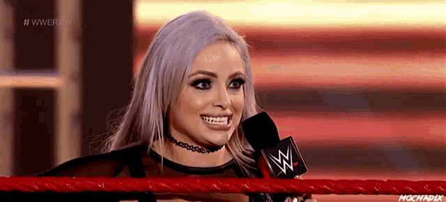 a woman in a wrestling ring is smiling and holding a microphone