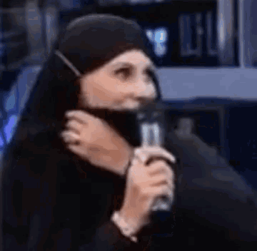 a woman wearing a hijab is holding a microphone .