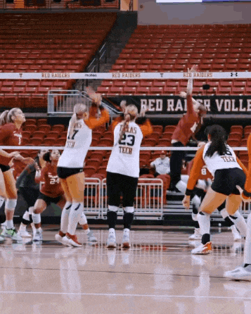 a volleyball game is being played in front of a red raiders sign