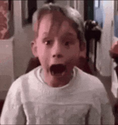 a young boy is making a surprised face with his mouth open in a room .