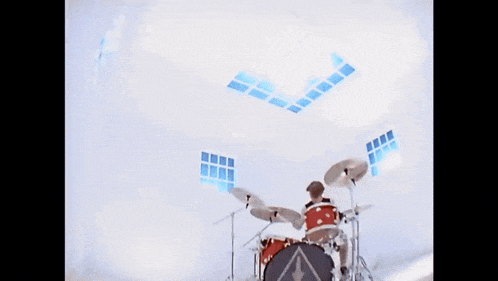 a man with long hair is playing a guitar in a white room .