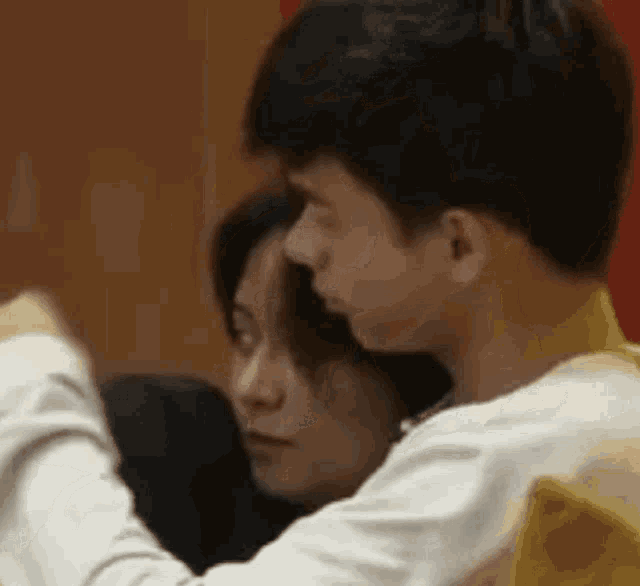 a man and a woman are sitting next to each other and hugging .