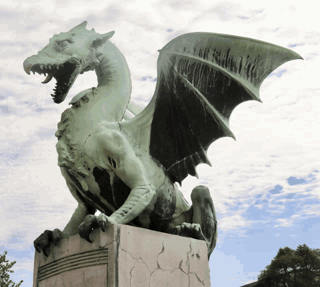 a statue of a green and black dragon with wings against a cloudy sky