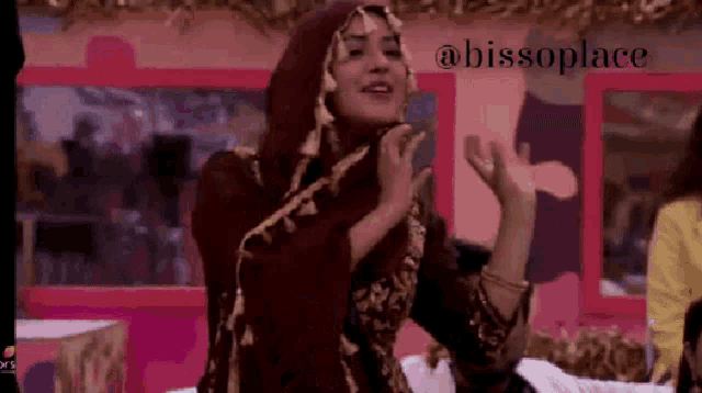 a woman in a hijab is dancing in front of a pink wall with the words bissoplace on it