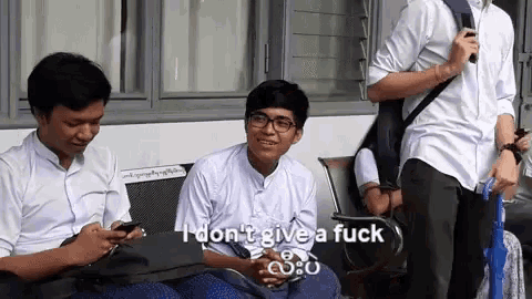 a group of young men are sitting on a bench and one of them says i don t give a fuck