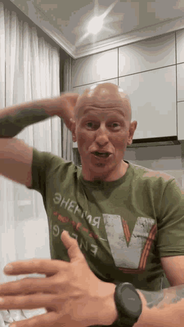 a man wearing a green t-shirt with the letter v on it