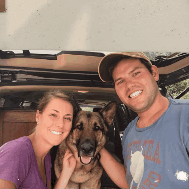 a man wearing a t-shirt that says ' alaska ' on it poses with a woman and a dog
