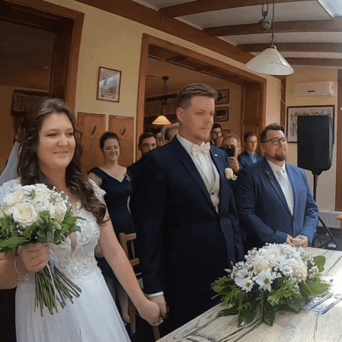 a bride and groom are holding hands in front of a table with flowers
