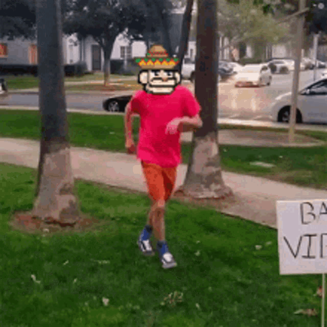 a man in a red shirt and orange shorts is running past a sign that says ba video