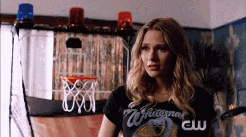 a woman in a whitesnake t-shirt stands in front of a basketball hoop