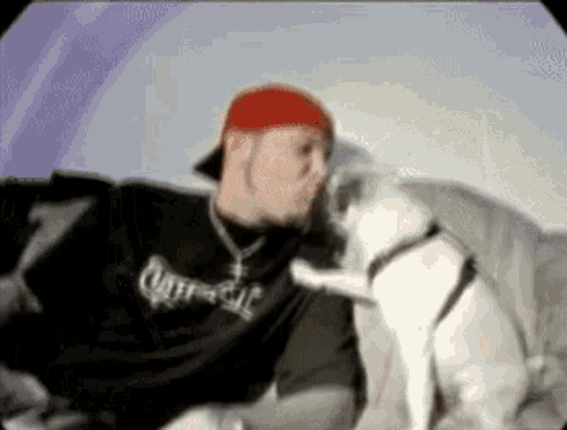 a man in a black shirt that says cliffside kisses a small white dog