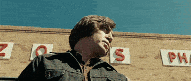 a man in a denim jacket stands in front of a brick building with a sign that says zoos pharmacy
