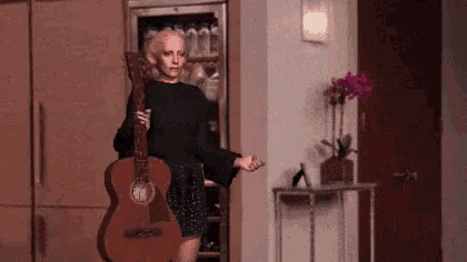 a woman is holding a guitar with the number 12 on the neck