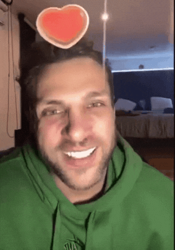 a man wearing a green hoodie with a heart on his head .
