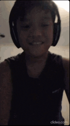 a young boy wearing headphones and a black tank top smiles for the camera .