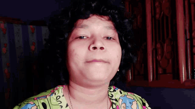 a woman with curly hair is wearing a green shirt with cartoon characters