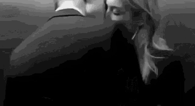 it is a black and white photo of a man and woman kissing .