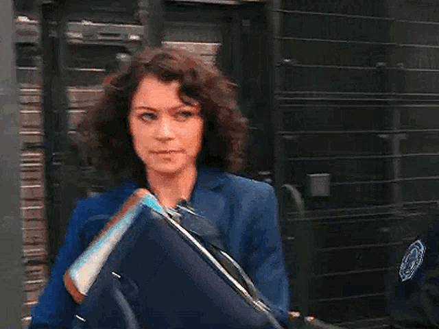 a woman in a blue jacket is holding a briefcase