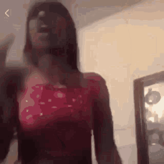 a woman in a red top stands in front of a mirror