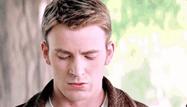 a close up of a man 's face with his eyes closed wearing a brown jacket .