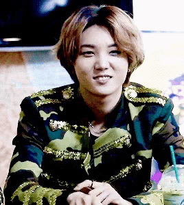 a young man in a camouflage jacket is smiling and looking at the camera