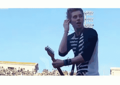 a man in a striped shirt is playing a guitar on a stage .
