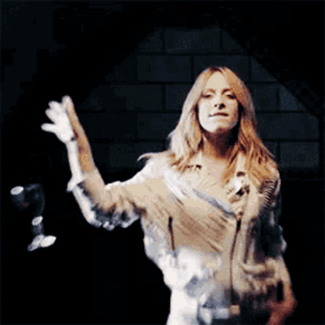 a woman in a fringed shirt is waving her hand in the air