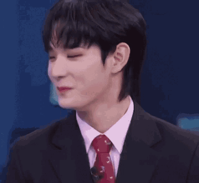 a man in a suit and tie is smiling with his eyes closed .