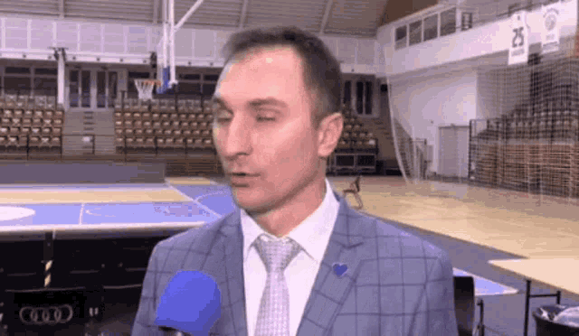 a man wearing a suit and tie is talking into a microphone