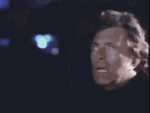 a close up of a man 's face in a dark room with his mouth open .
