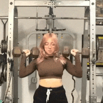a woman is lifting dumbbells in a gym .