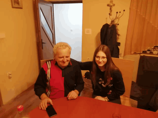 a man and a girl are sitting at a table with a bottle of water on the table