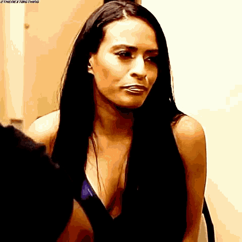 a woman with long black hair is standing in front of a mirror looking at herself .