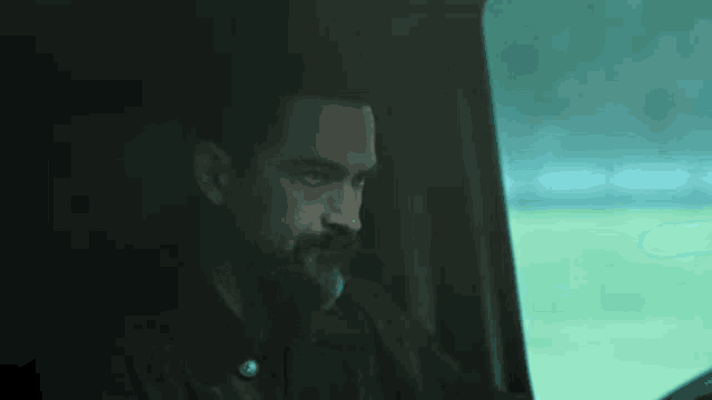 a man with a beard is sitting in the back seat of a car .