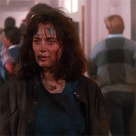 a woman with blood on her face is walking down a hallway .
