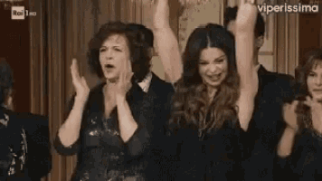 a group of people are standing next to each other with their arms in the air .