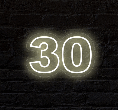 the number 30 is glowing in the dark on a brick wall
