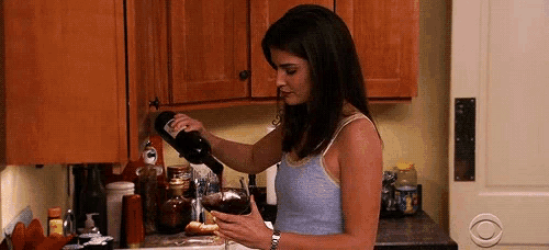 a woman is pouring a bottle of wine into a glass .